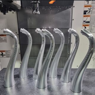 Batch of machined curved aluminium robotic arms displayed in CNC machining cell