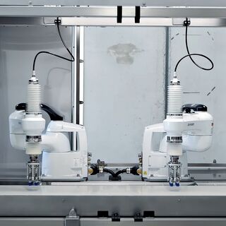 Dual SCARA robotic arms operating inside an automated assembly station
